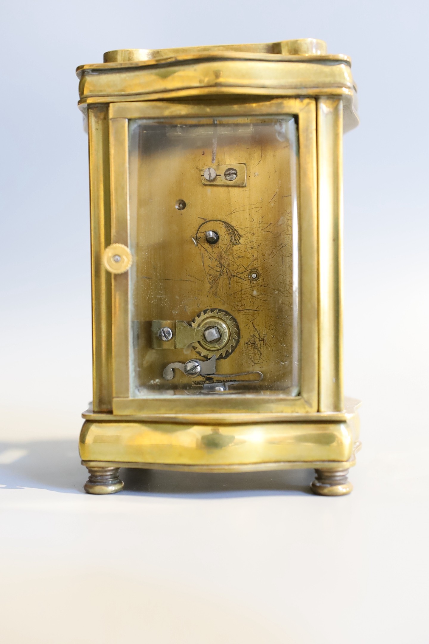 An early 20th century French lacquered brass carriage timepiece, of serpentine form, in red morocco case, height 12cm